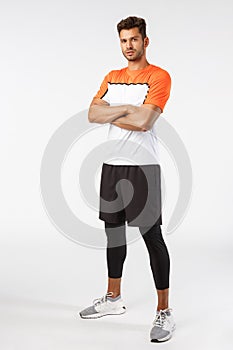 Confidence, sport and fitness concept. Vertical shot good-looking bearded handsome young sportsman in activewear, cross