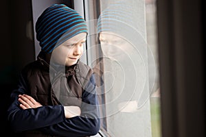 Confident 7 year old boy looks out the window