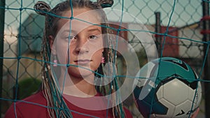 Confident adolescent girl emphasizes passion for football posing with ball on soccer field