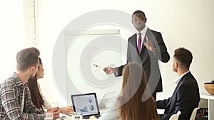 Confident african-american businessman giving presentation to multi-ethnic group with flipchart