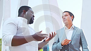 Confident African-American businessman and his colleague in front of modern office building. Financial investors are