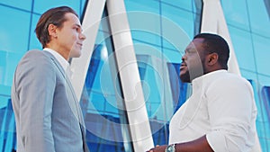 Confident African-American businessman and his colleague in front of modern office building. Financial investors are