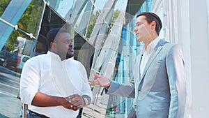 Confident African-American businessman and his colleague in front of modern office building. Financial investors are