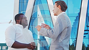 Confident African-American businessman and his colleague in front of modern office building. Financial investors are