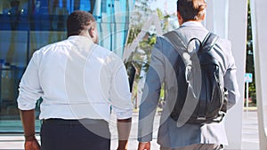 Confident African-American businessman and his colleague in front of modern office building. Financial investors are