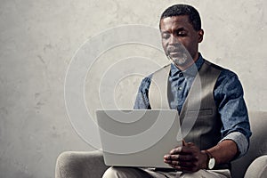 confident african american businessman with laptop sitting