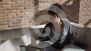 Confident African American female architect sitting in home office with blueprint on sunny morning. Portrait of