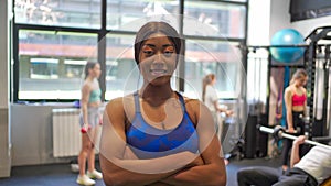 Confident African American fitness woman looking at camera and smiling while posing in gym.