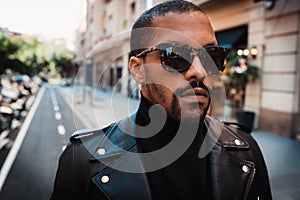 Confident african american man wearing on sunglasses and black leather jacket outdoor. Street wear fashion black man