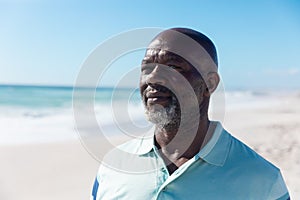 Confident african american retired senior bald man looking away at beach on sunny day