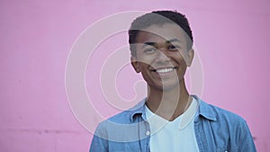 Confident african-american teenager smiling to camera adjusting hair, puberty
