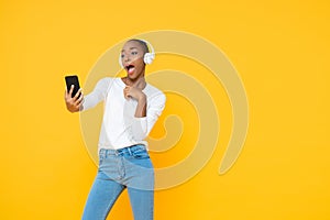 Confident African American woman wearing headphones listening to music from mobile phone