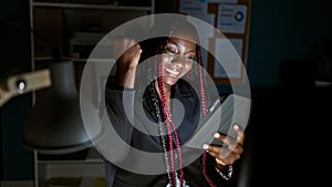 Confident african american woman worker celebrating business success with touchpad at office, a beautiful portrait of a smiling,