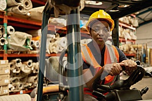 Confident African female forklift operator working in a storehouse