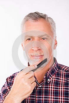 Confident aged man combing his beard