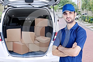 Confident Arabian courier standing near his van