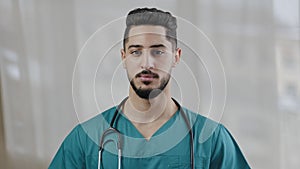 Confident arabian hispanic man intern practitioner male nurse surgeon wear medical uniform with stethoscope standing in
