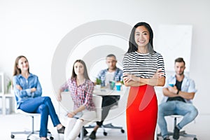 Confident asian business leader with her team on background