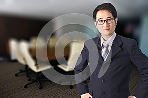 Confident Asian businessman standing in front of meeting room.