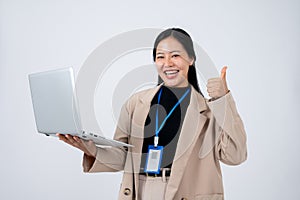A confident Asian businesswoman holding a laptop and showing her thumb up, isolated white background