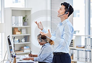 Confident asian customer service rep standing and talking on headset in office. Man working in call center consulting