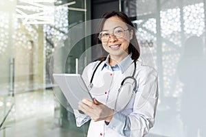 Confident asian female doctor in clinic office offering remote consultation