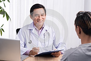 Confident asian male doctor discussing diagnosis with patient in