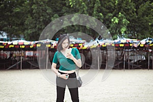 Confident Asian woman using mobile phone on the beach,Happy and smiling,Relax time,Summer travel concept