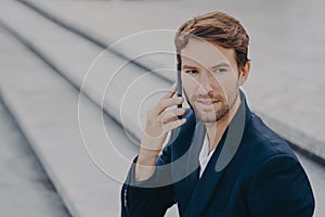 Confident attractive businessman in suit talking on smartphone outside