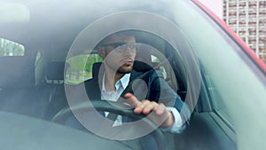 Confident attractive elegant man in business suit driving car in the city. Transport, business and people concept. Slow