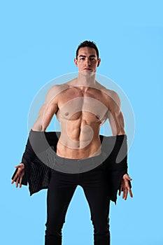 Confident, attractive young man with open sweater on muscular torso