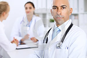 Confident bald doctor man with medical staff at the hospital