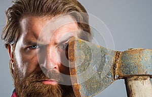 Confident bearded man with axe near face. Serious lumberjack. Sharp blade. Male with ax. Closeup portrait.