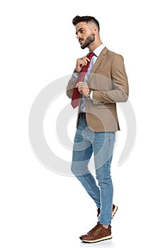 Confident bearded man looking to side and adjusting red tie