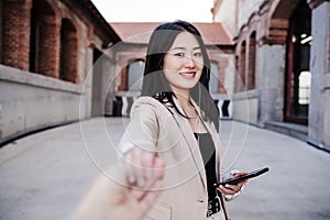 Confident beautiful chinese business woman using mobile phone in city.Holding hand with friend. POV