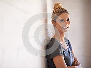 Confident and beautiful. Portrait of an attractive young woman leaning against a brick wall.