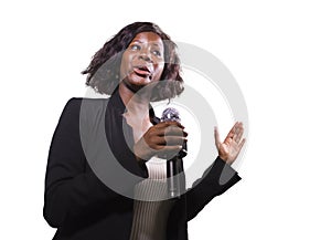 Confident black African American business woman with microphone speaking in auditorium at corporate event or seminar giving