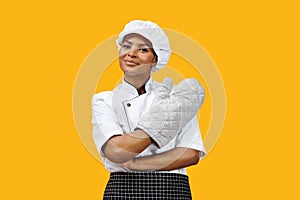 Confident black female chef with crossed arms wearing an oven mitt