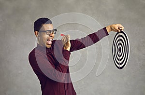 Confident black man aiming dart at shooting target bullseye as metaphor for setting business goal