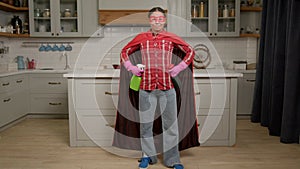 Confident black woman with spray detergents posing in superheroes mask and cape