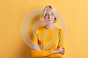 Confident blode model standing over yellow background, free time