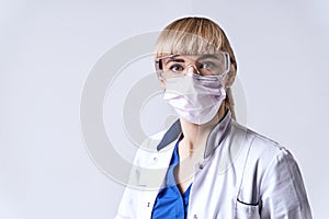 Confident blonde female doctor wearing protective face mask. Portrait on light grey background.