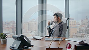 Confident boss taking coffee break sitting luxury office looking window close up