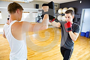 Confident Boxer Punching Bag Held By Instructor In Gym