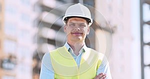 Confident builder, foreman or inspector in protective helmet and vest standing on construction site on street, tracking