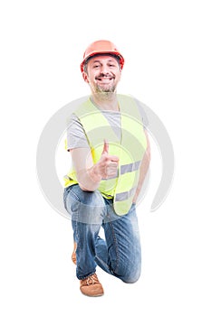 Confident builder kneeling and showing like sign