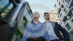 Confident business couple posing street. Two successful partners standing