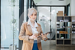 Confident business expert attractive smiling young woman holding digital tablet on desk in creative office