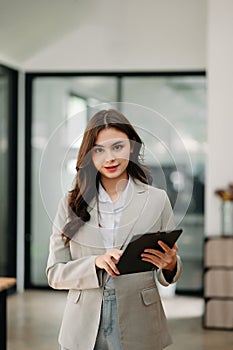 Confident business expert attractive smiling young woman holding digital tablet on desk in creative office