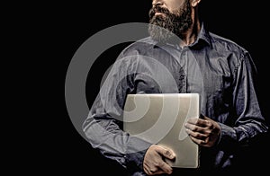 Confident business expert. Confident young handsome man in shirt holding laptop. Bearded male businessman holding a